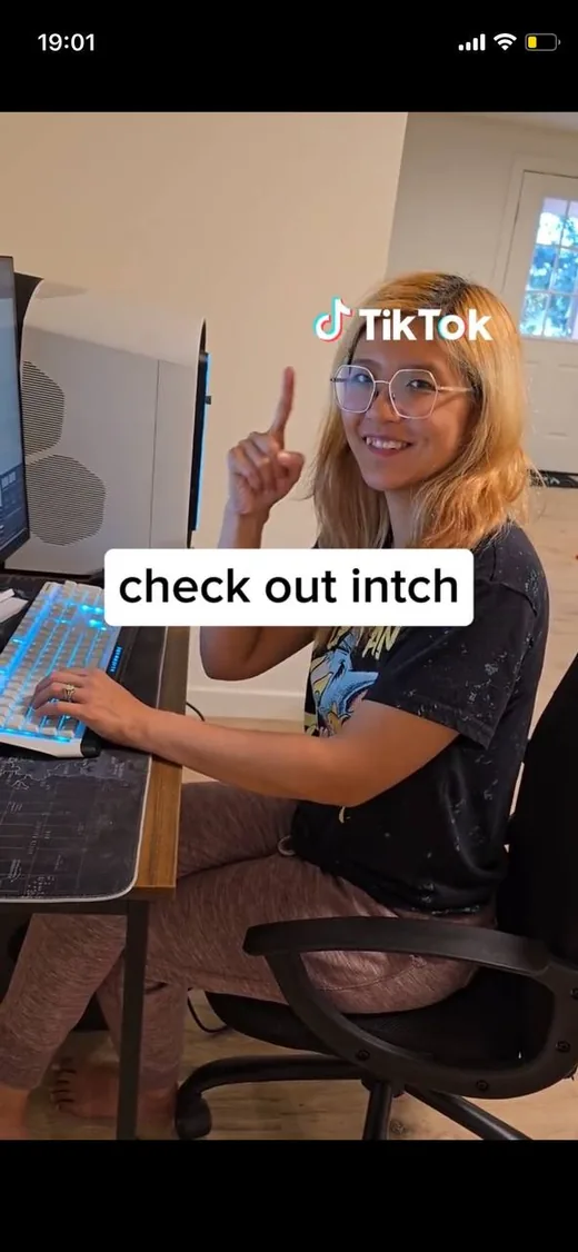 Screenshot of a TikTok video showing a smiling woman at her computer desk pointing upward next to the caption 'check out intch'.